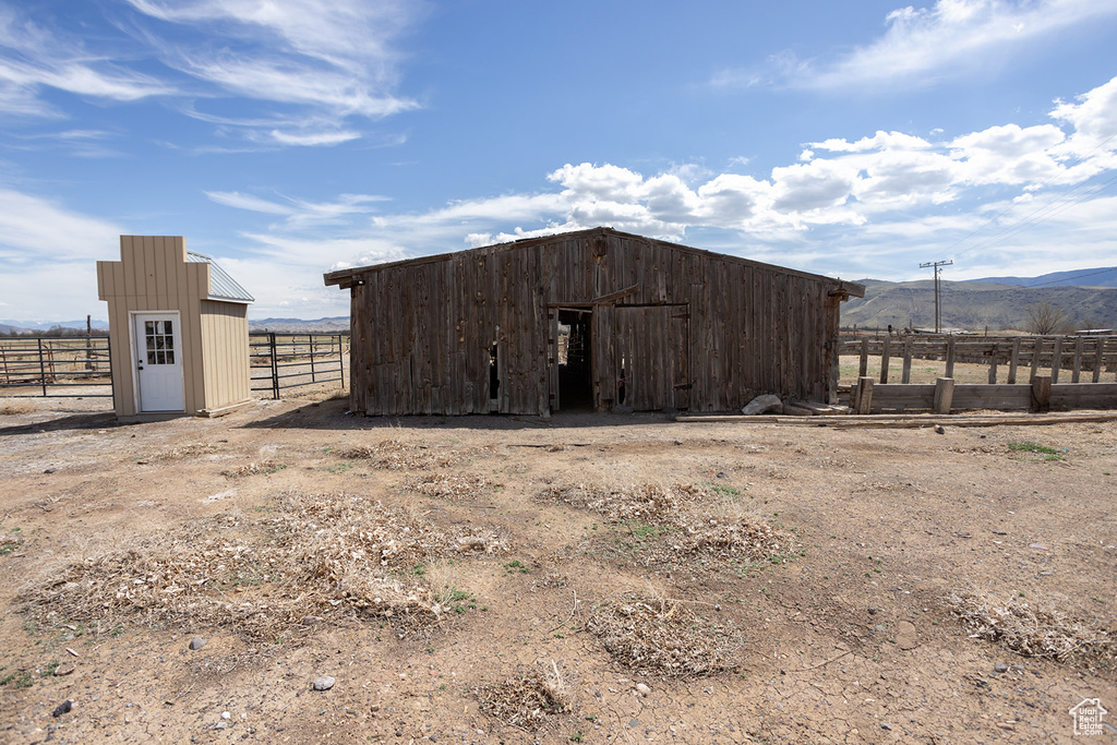 View of pole building with fence, a rural view, and a mountain view