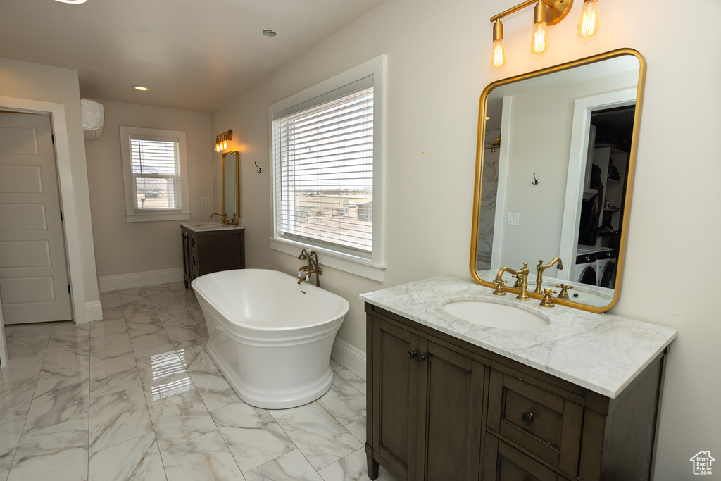 Full bathroom featuring a sink, baseboards, two vanities, a freestanding bath, and marble finish floor