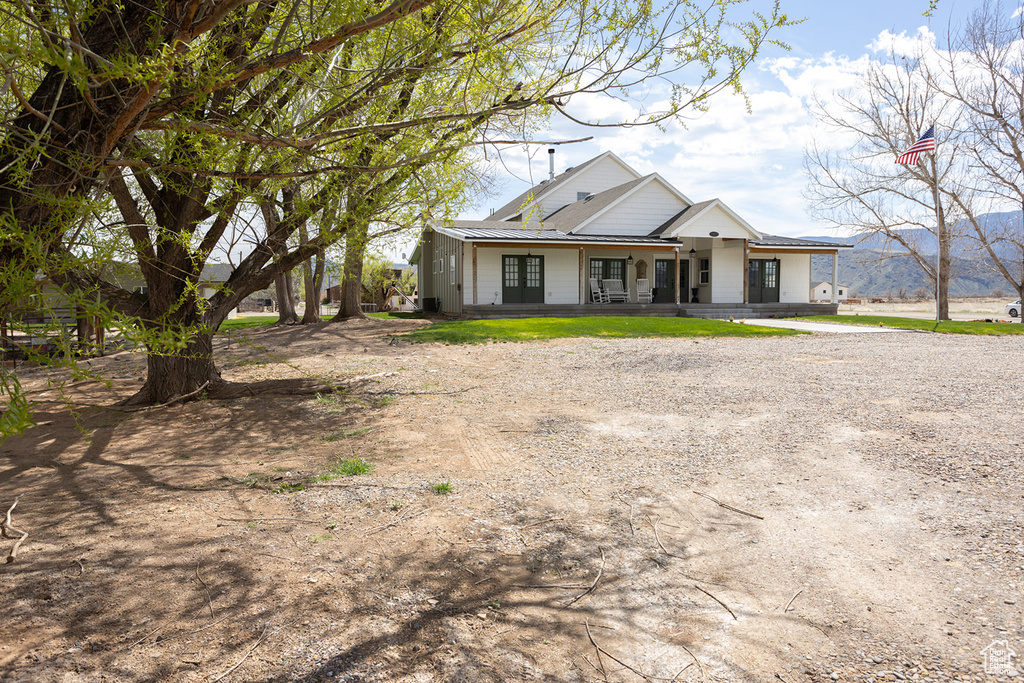 View of front of house featuring a porch, driveway, and metal roof