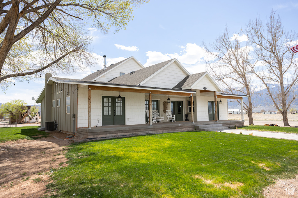 Modern inspired farmhouse with roof with shingles, board and batten siding, a porch, and a front lawn