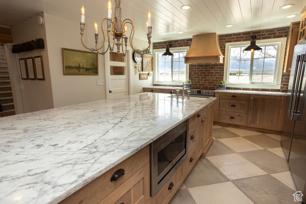 Kitchen with light stone counters, custom range hood, a sink, appliances with stainless steel finishes, and recessed lighting
