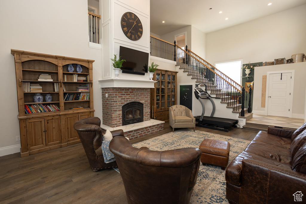 Living room featuring stairs, dark wood-style flooring, a fireplace, baseboards, and a towering ceiling