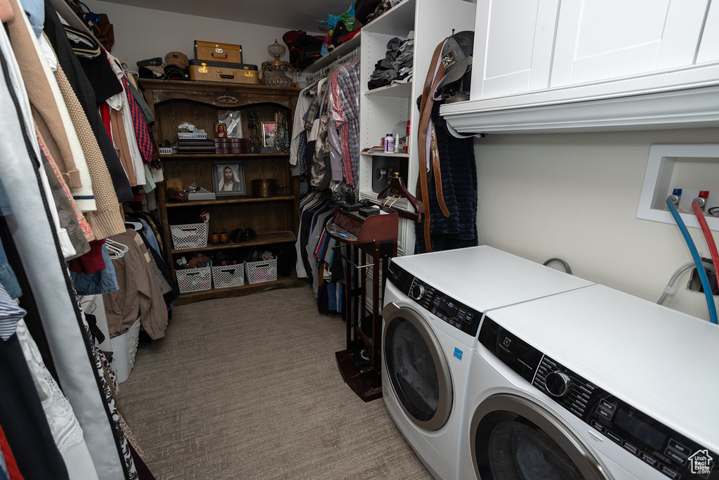 Clothes washing area featuring cabinet space, washing machine and clothes dryer, and carpet floors