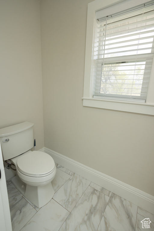 Bathroom with toilet, marble finish floor, and baseboards