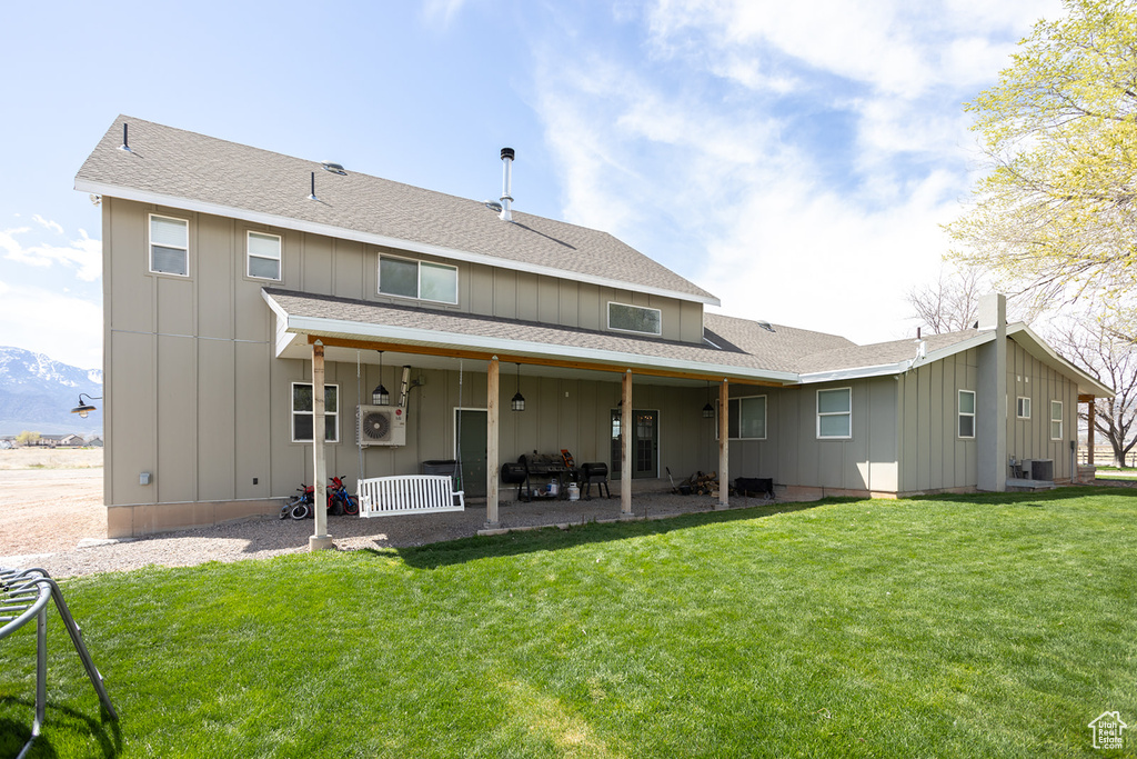 Rear view of house with a patio, board and batten siding, a shingled roof, and a yard
