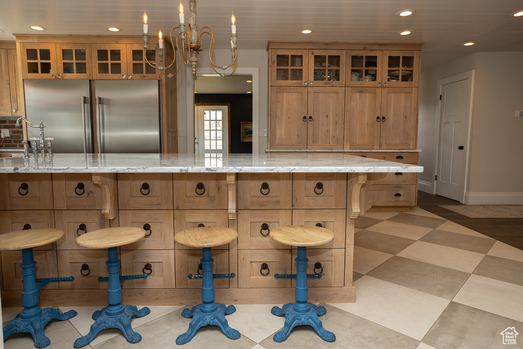 Kitchen with recessed lighting, brown cabinets, glass insert cabinets, a kitchen bar, and stainless steel built in fridge