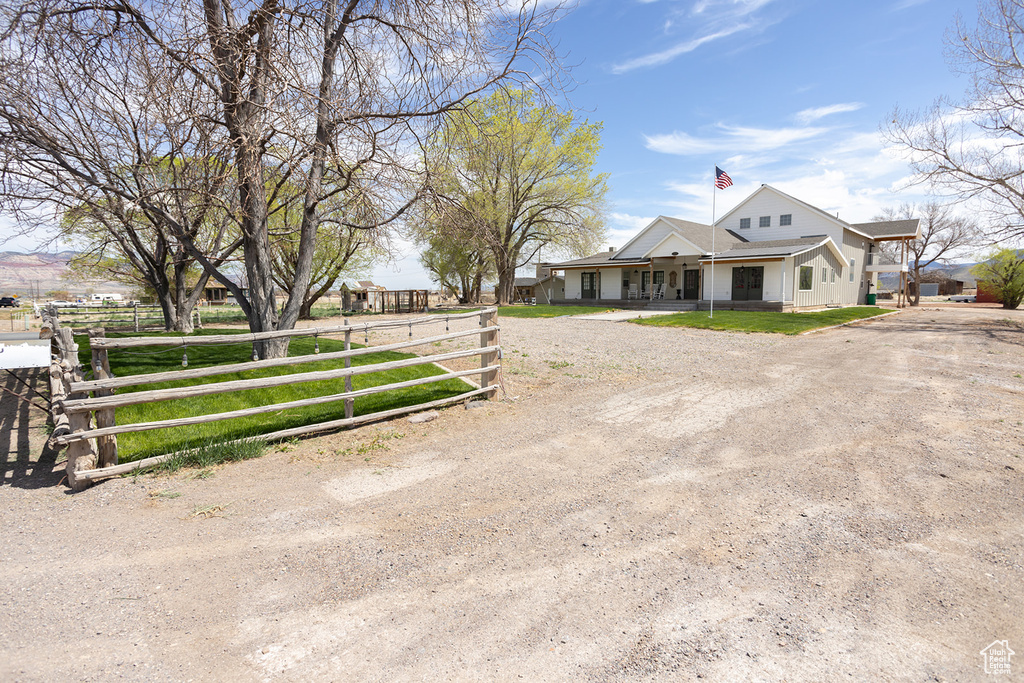 View of front facade featuring fence, a chimney, driveway, and a porch
