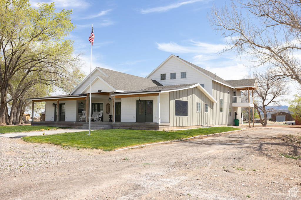 Modern farmhouse style home with driveway, board and batten siding, a porch, and a shingled roof