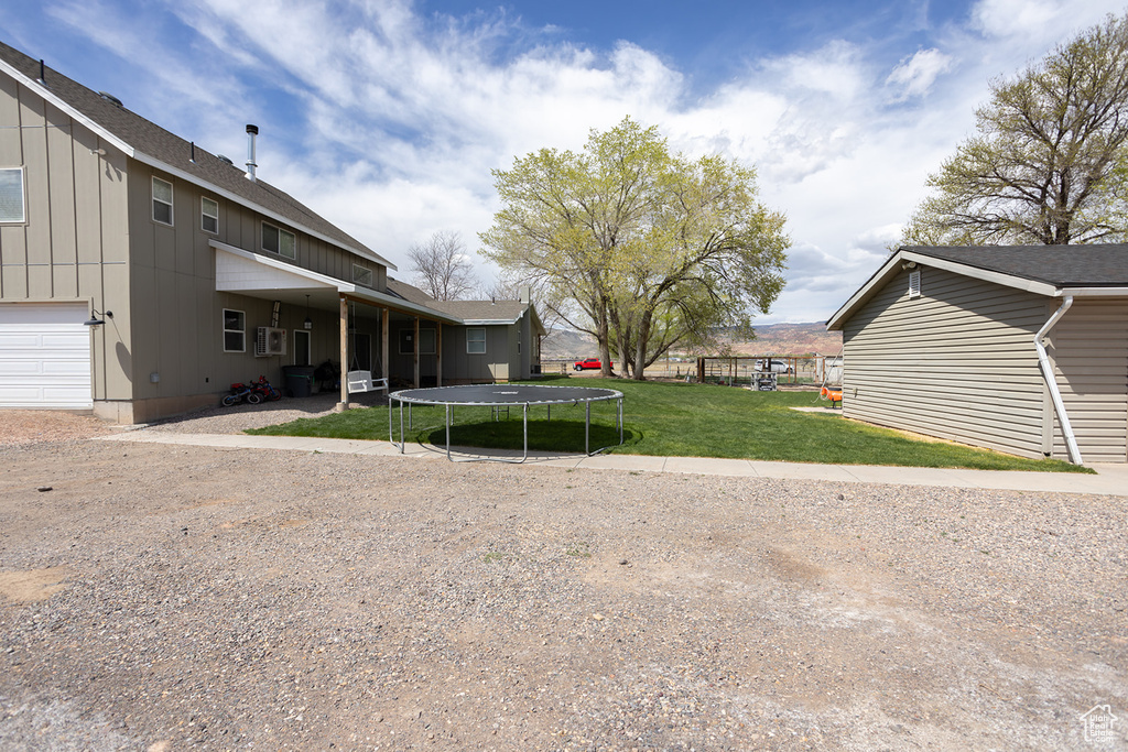 View of yard featuring a garage and a trampoline