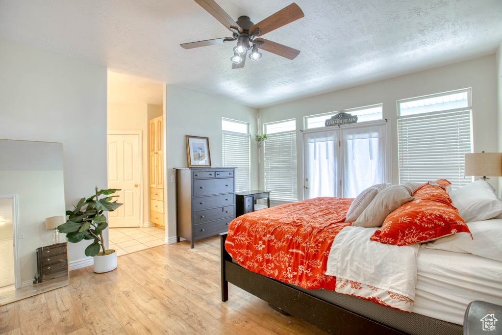 Bedroom with connected bathroom, light wood-type flooring, a ceiling fan, baseboards, and a textured ceiling