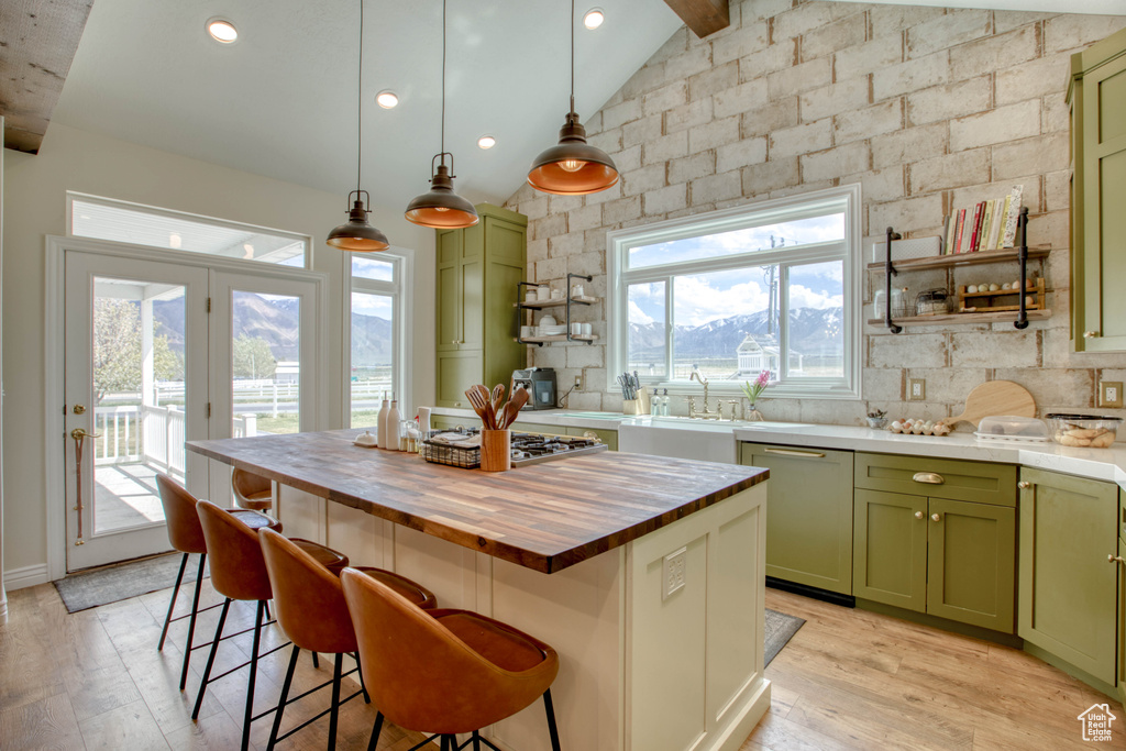 Kitchen featuring lofted ceiling with beams, butcher block countertops, stainless steel appliances, green cabinets, and light wood finished floors
