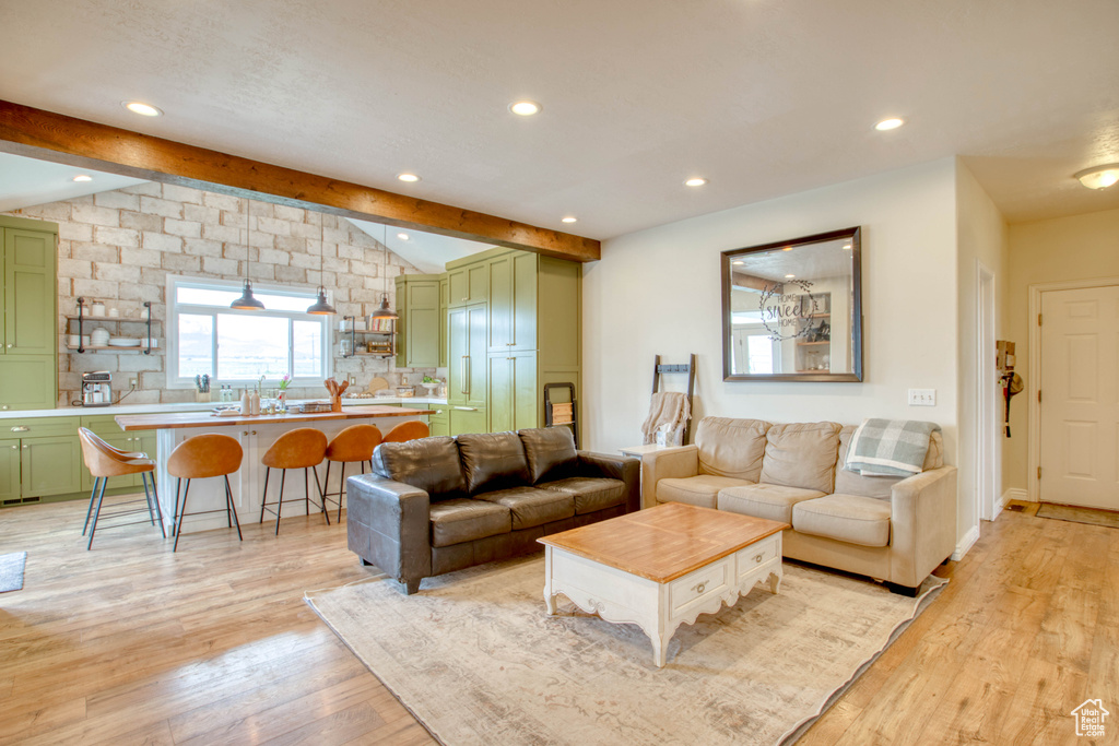 Living area with recessed lighting, vaulted ceiling with beams, and light wood-style flooring