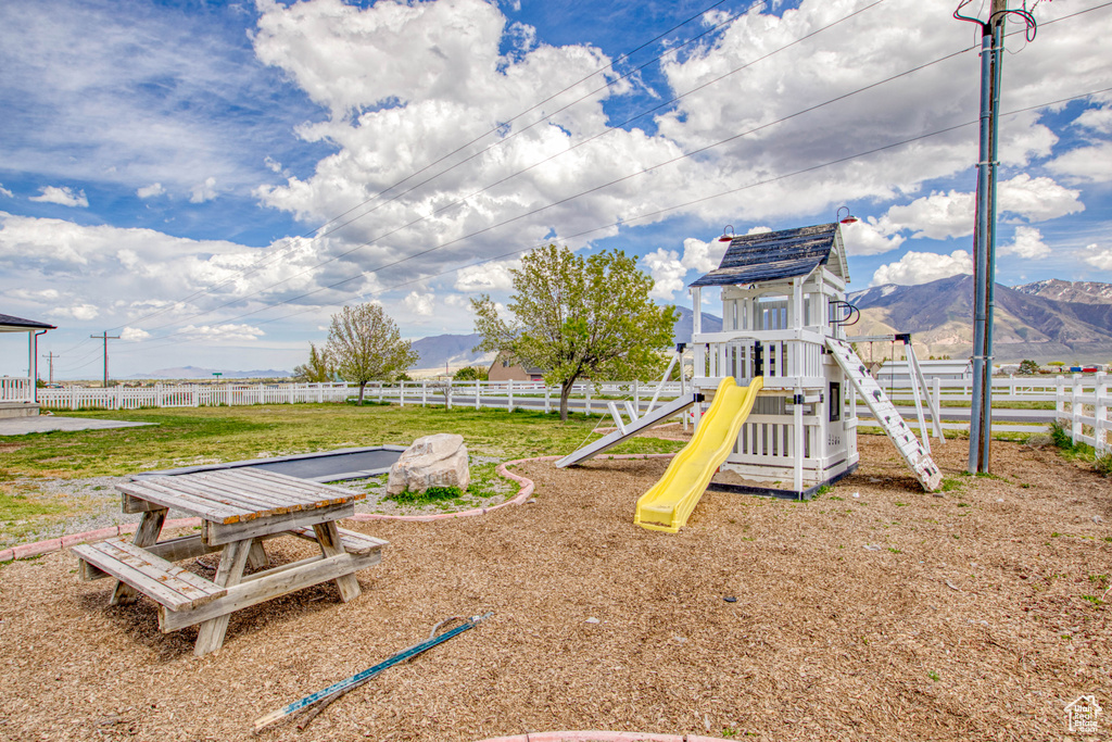 Community play area with a mountain view, fence, and a yard