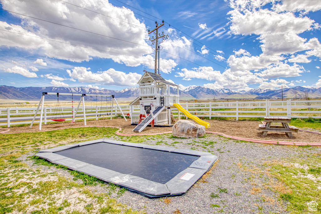 View of yard featuring a mountain view, fence, and a playground