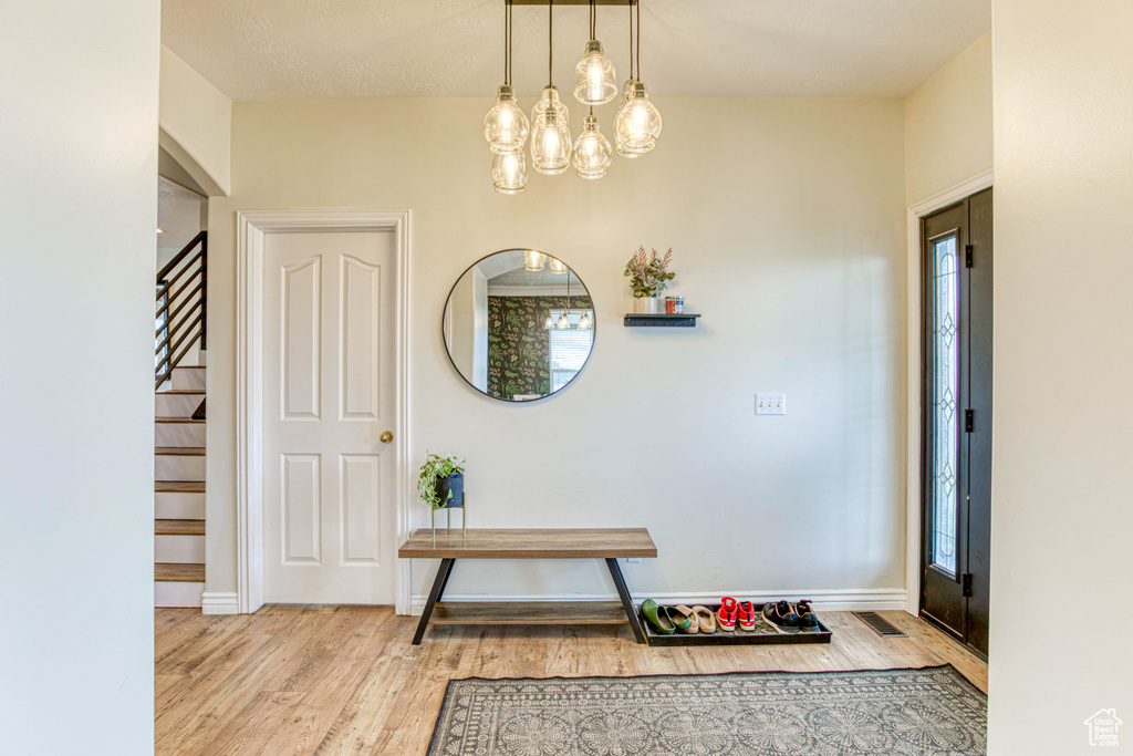 Foyer with visible vents, stairway, wood finished floors, and a chandelier