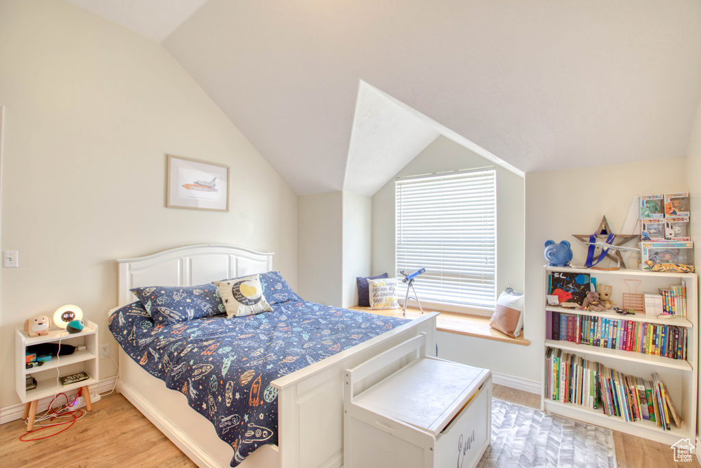 Bedroom with baseboards, light wood finished floors, and vaulted ceiling