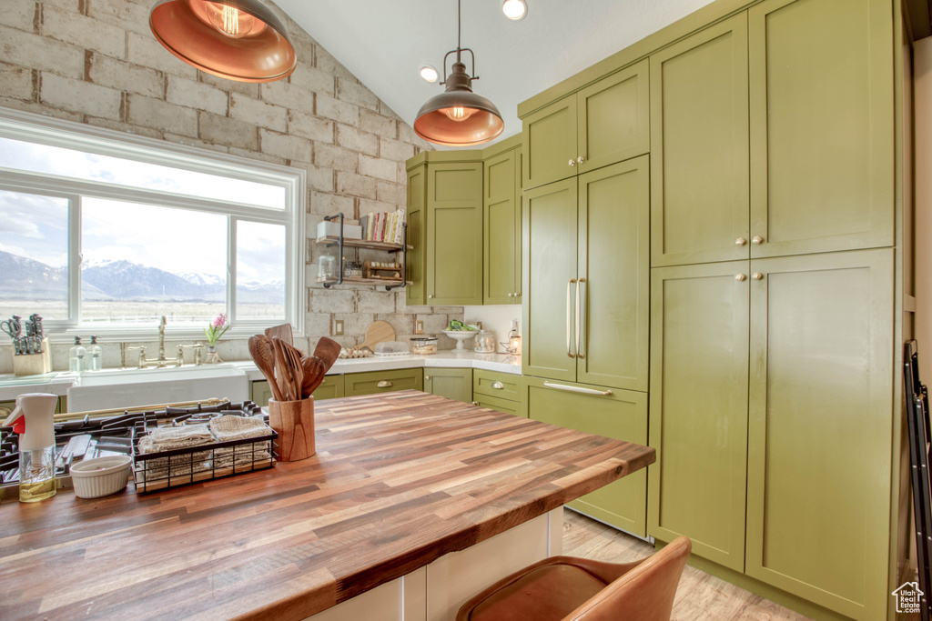 Kitchen featuring green cabinetry, wooden counters, paneled built in refrigerator, and lofted ceiling