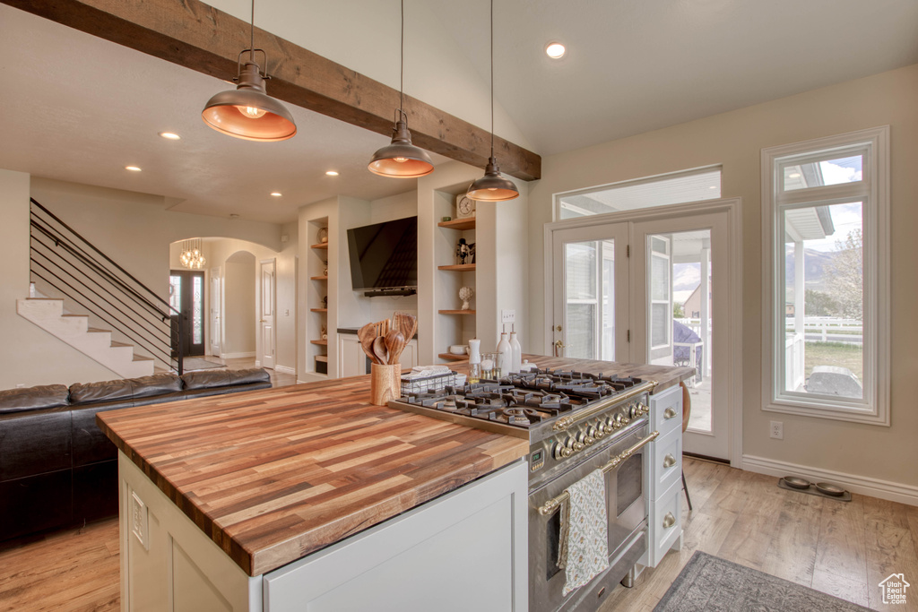 Kitchen featuring wooden counters, stainless steel stove, arched walkways, and open floor plan