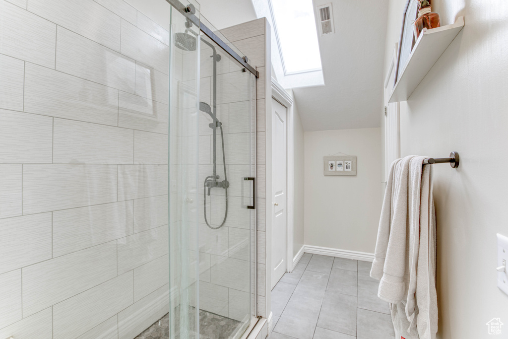 Bathroom featuring a shower stall, tile patterned floors, visible vents, baseboards, and a skylight