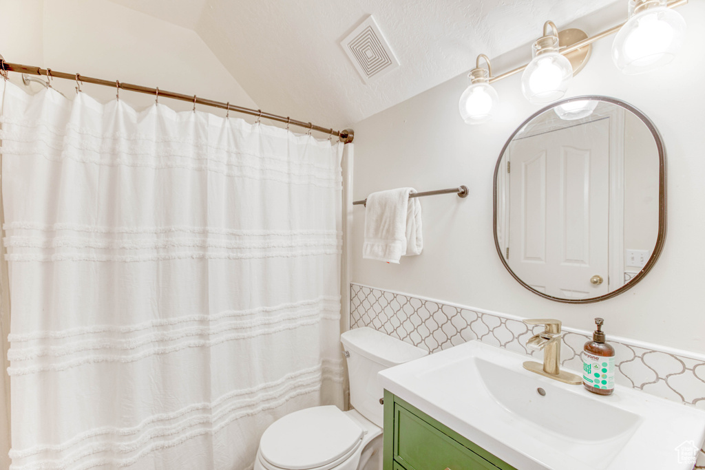 Bathroom featuring tile walls, vanity, toilet, a wainscoted wall, and visible vents
