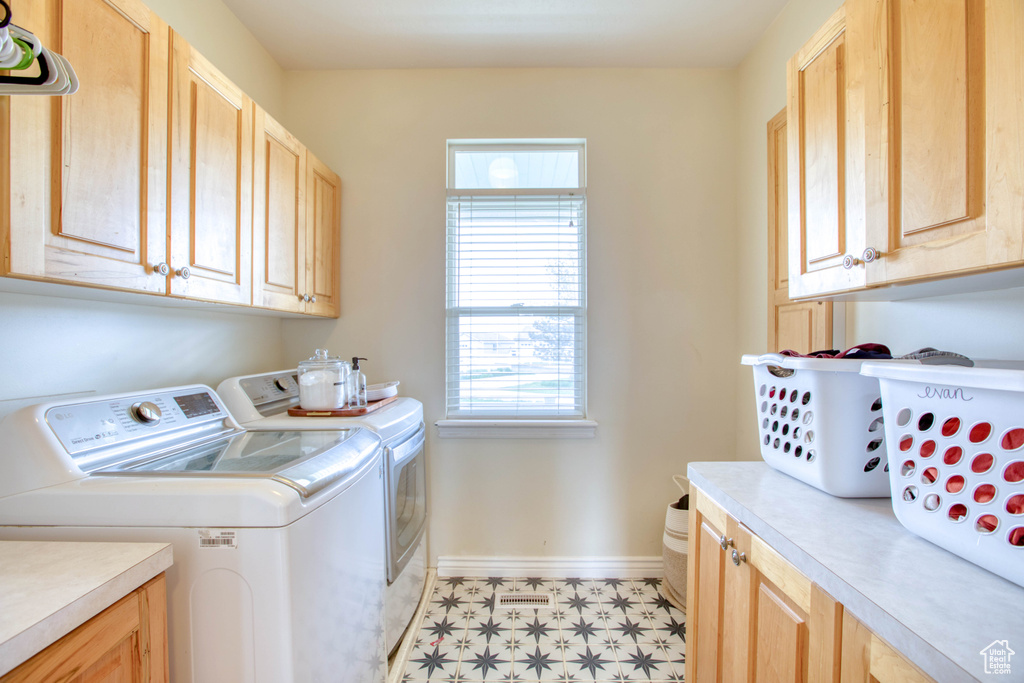 Laundry area with washer and dryer, cabinet space, baseboards, and light floors