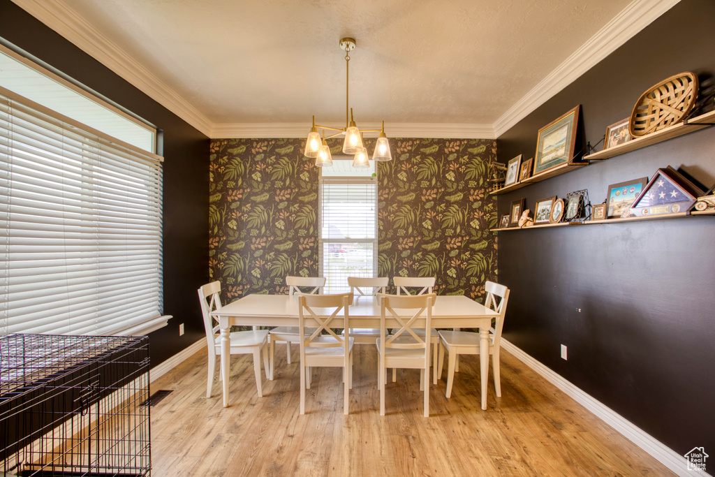 Dining area featuring an inviting chandelier, ornamental molding, and wallpapered walls