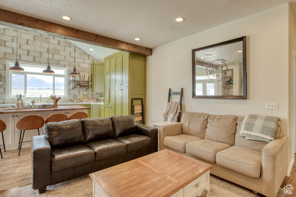 Living area featuring a healthy amount of sunlight, recessed lighting, light wood finished floors, and vaulted ceiling with beams
