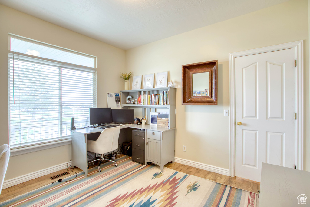 Office featuring light wood-type flooring, visible vents, and baseboards