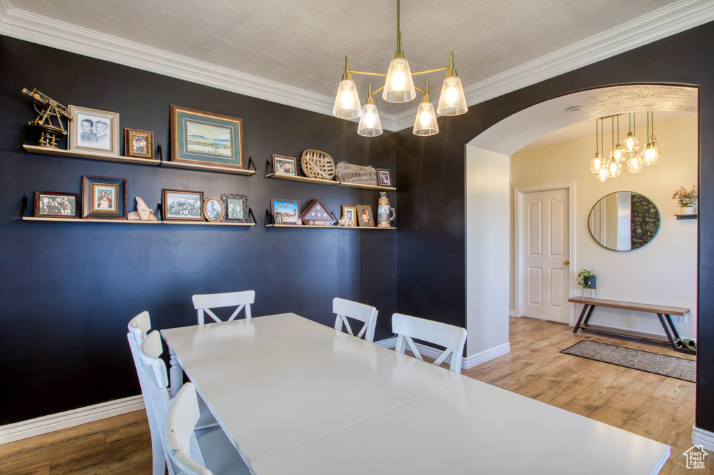 Dining area featuring crown molding, arched walkways, an inviting chandelier, and baseboards
