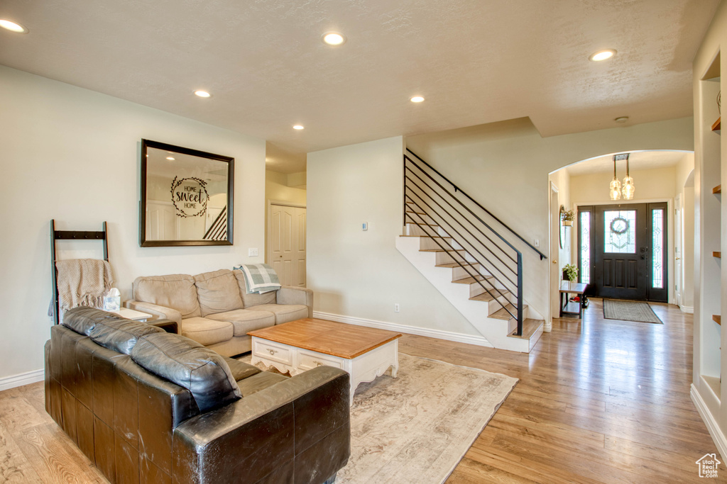 Living room featuring stairway, light wood-style floors, baseboards, arched walkways, and recessed lighting