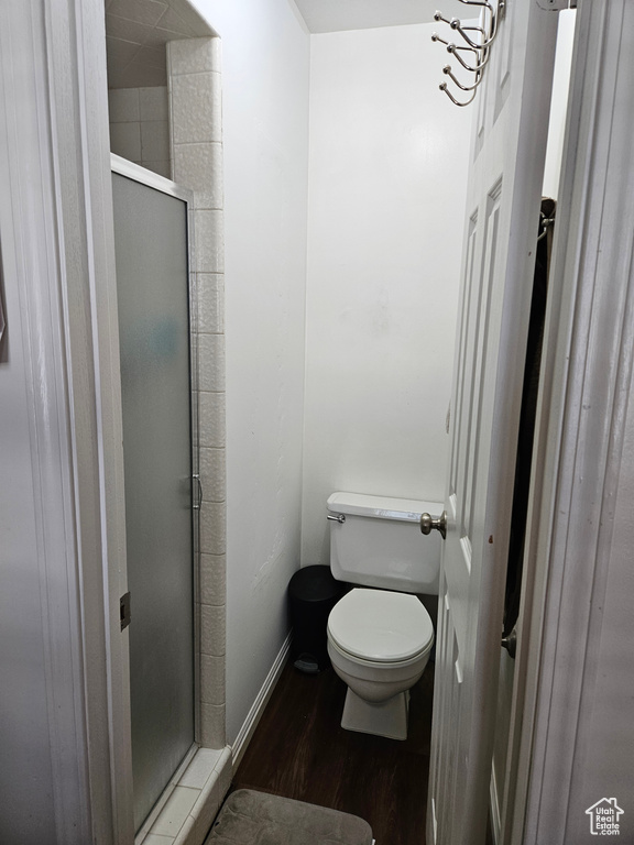 Full bath with a shower stall, wood finished floors, toilet, and baseboards