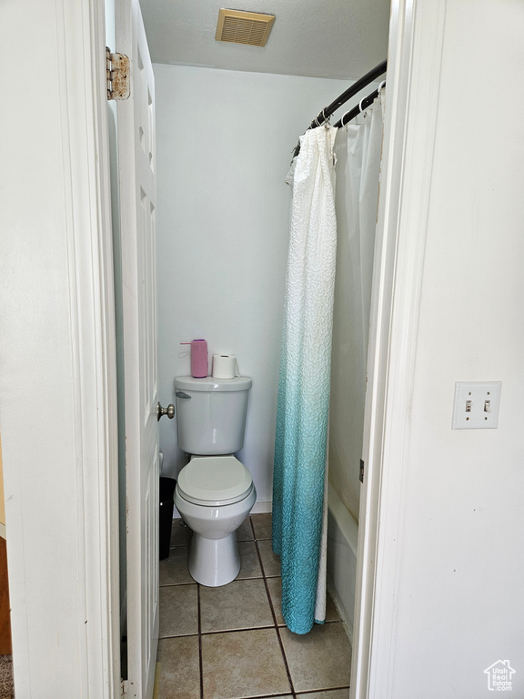 Bathroom featuring toilet, tile patterned flooring, and a shower with shower curtain