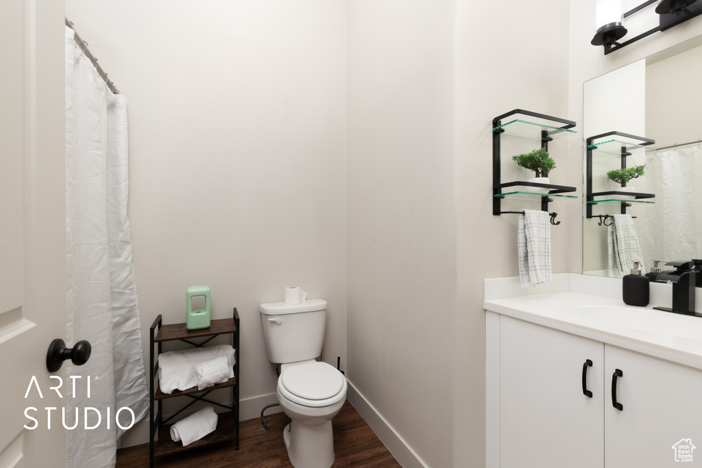 Full bath with wood finished floors, toilet, vanity, and baseboards