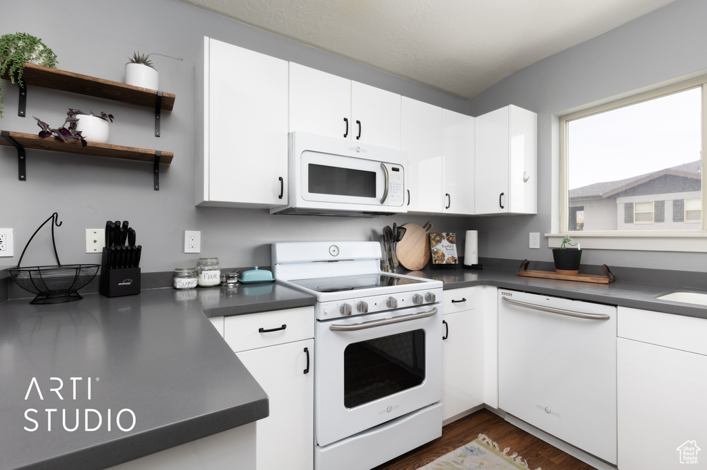 Kitchen featuring white cabinetry, dark countertops, white appliances, and dark wood-type flooring