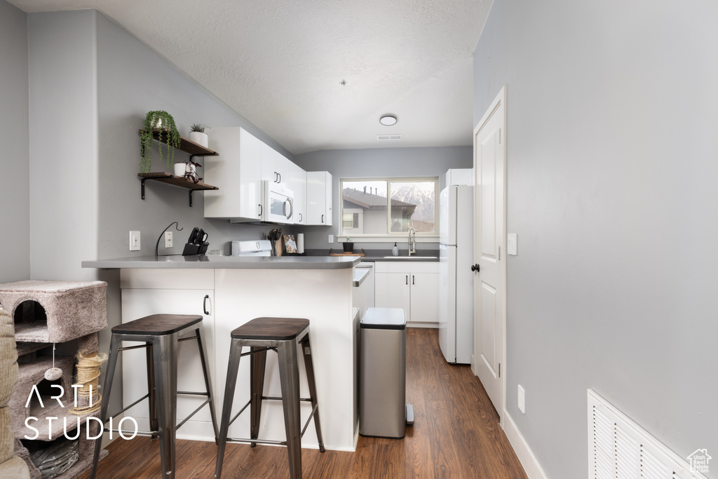 Kitchen with a sink, open shelves, a breakfast bar, a peninsula, and white appliances