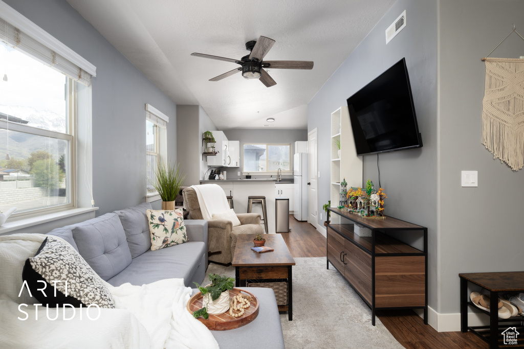 Living area featuring visible vents, a ceiling fan, baseboards, and light wood-style floors