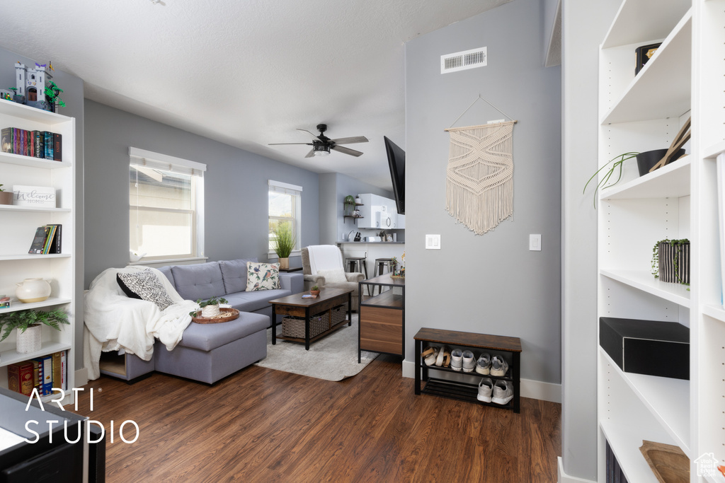 Living area with dark wood-style floors, visible vents, ceiling fan, and baseboards