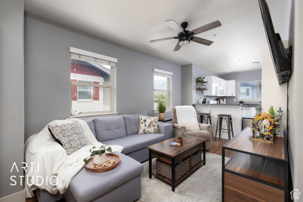 Living room with a healthy amount of sunlight, light wood finished floors, and ceiling fan