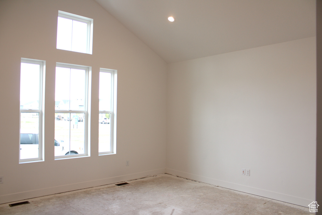 Unfurnished room featuring a high ceiling, visible vents, and baseboards