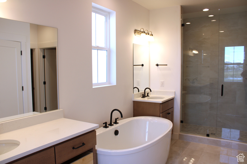 Bathroom with two vanities, a soaking tub, a stall shower, and a sink