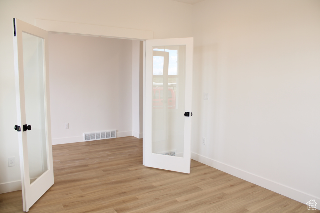 Unfurnished room featuring baseboards, visible vents, french doors, and light wood finished floors