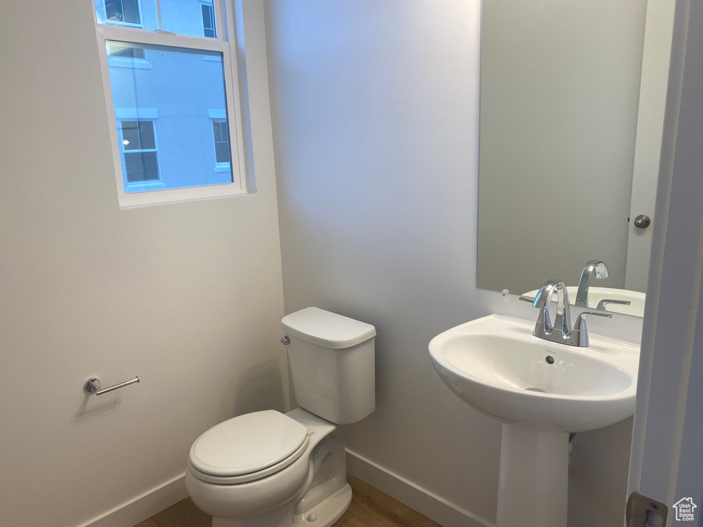 Bathroom with toilet, wood finished floors, and baseboards