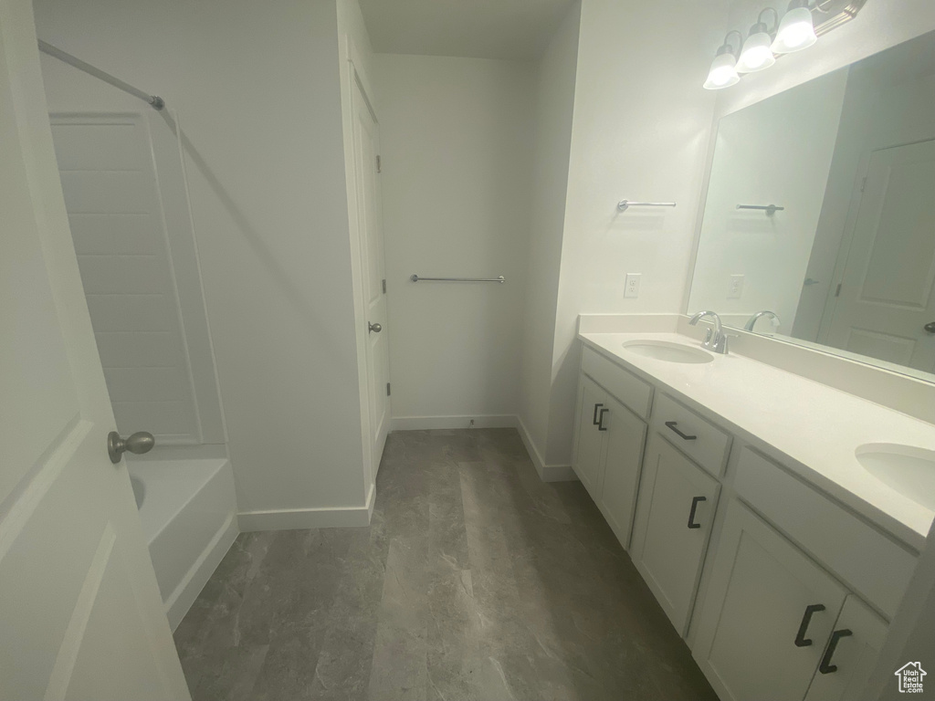 Full bathroom featuring double vanity, baseboards, and a sink