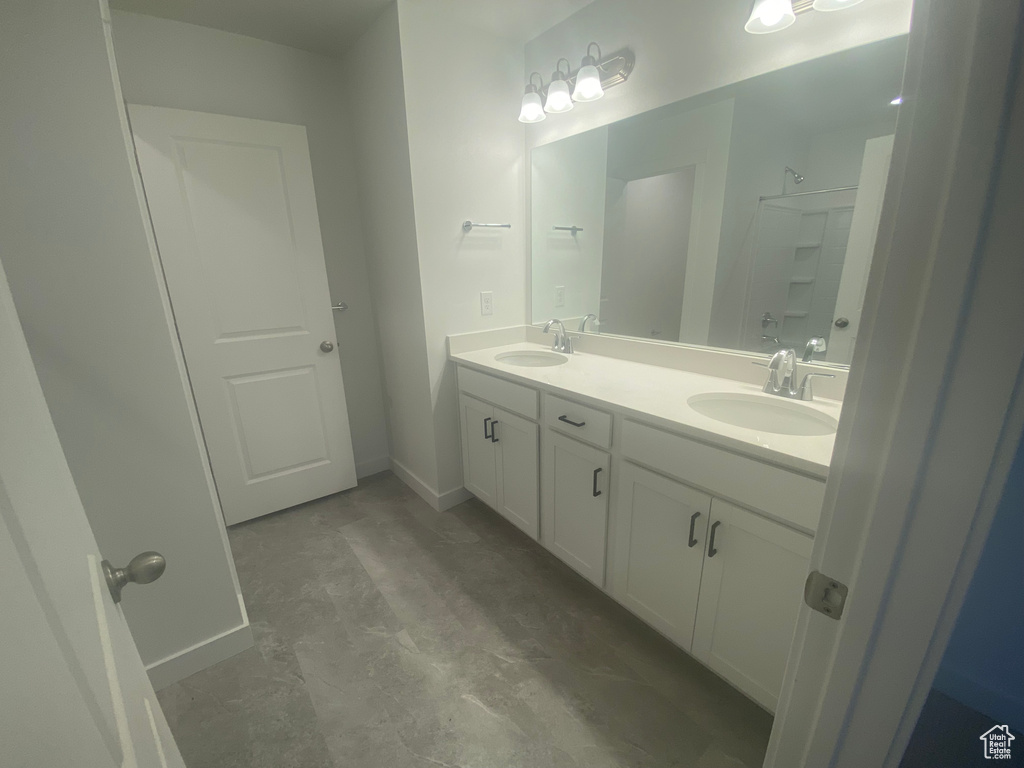 Full bathroom with baseboards, walk in shower, double vanity, and a sink