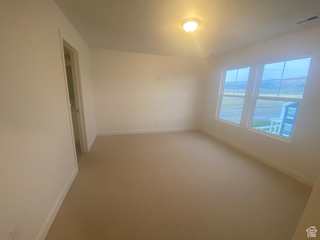 Spare room featuring visible vents, light carpet, and baseboards