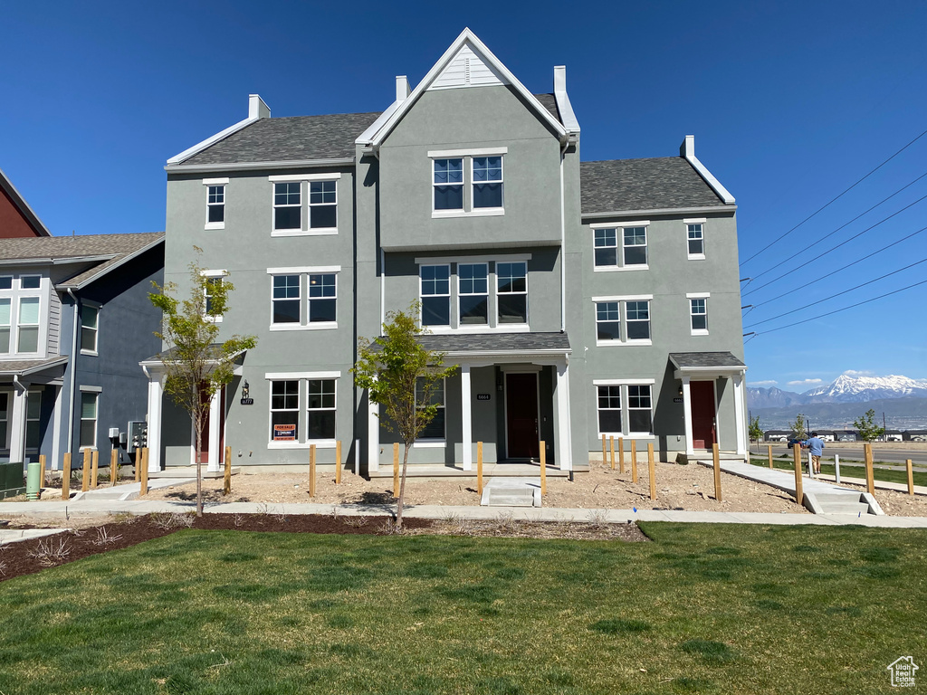 Rear view of property with a mountain view, stucco siding, and a yard