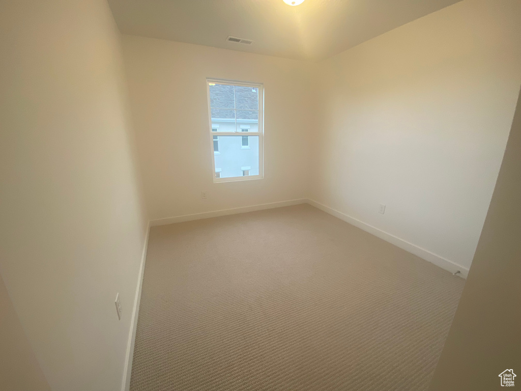 Unfurnished room featuring visible vents, light colored carpet, and baseboards