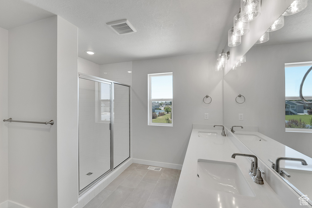 Bathroom featuring baseboards, a shower stall, double vanity, and recessed lighting