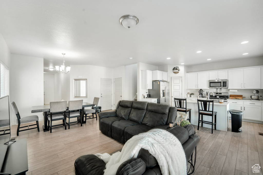 Living room featuring an inviting chandelier, recessed lighting, and light wood-style flooring