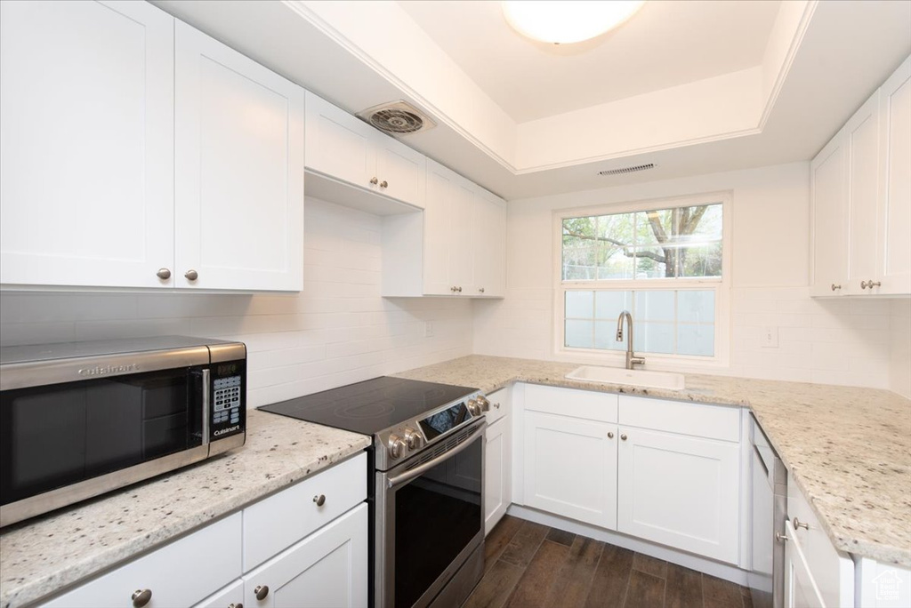 Kitchen with white cabinets, stainless steel appliances, decorative backsplash, and a sink